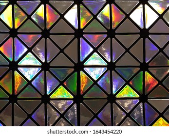 Graphic pattern in the form of a mosaic of triangles with a shiny glossy surface in neon colors. Concept background, abstraction.