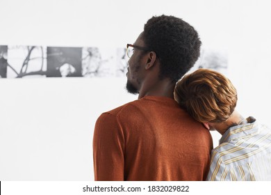 Graphic Portrait Of Mixed-race Couple Embracing While Looking At Paintings At Modern Art Gallery Exhibition, Copy Space