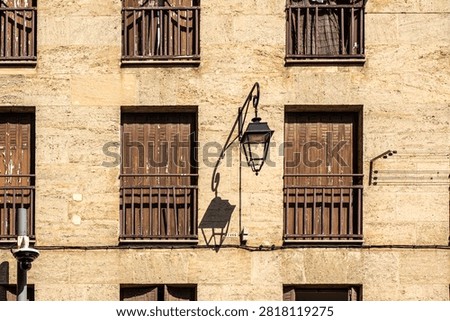 A graphic shadow from a lantern on the facade of the house, on the windows of closed shutters, warm shades of color prevail