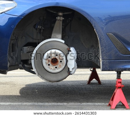 Graphite Coating on a Front Brake Disc of a Car Staying on a Red Jack
