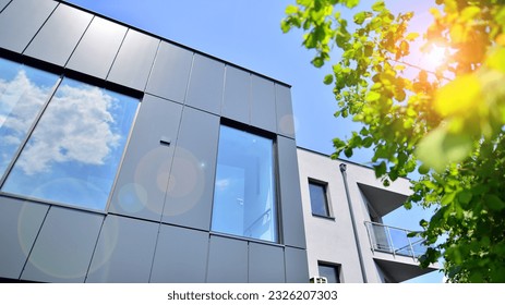 Graphite facade and large windows on a fragment of an office building against a blue sky. Modern aluminum cladding facade with windows.