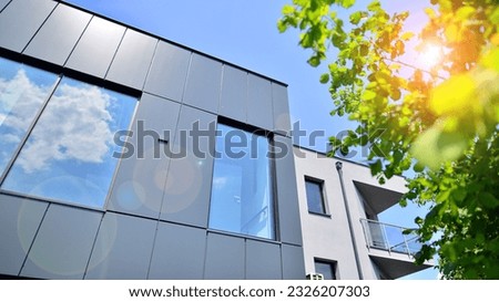 Graphite facade and large windows on a fragment of an office building against a blue sky. Modern aluminum cladding facade with windows.