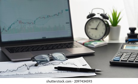 Graphs of movement of financial instrument on white sheet of paper, magnifying glass on graph, laptop, calculator,  sheets for notes lie on table - concept of finance, investment and  stock market.