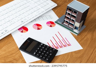 Graphs, real estate models, and a computer on the desk. - Shutterstock ID 2395795775