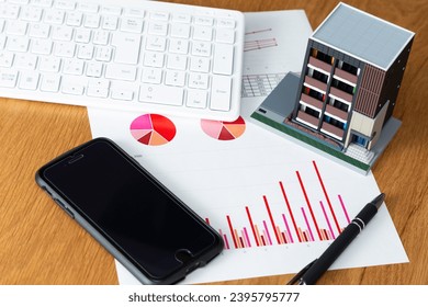 Graphs, real estate models, and a computer on the desk. - Shutterstock ID 2395795777
