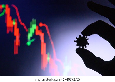 Graphs Representing The Stock Market Crash Caused By The Coronavirus. Hands Silhouette Holds Corona Virus