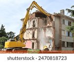 Grapple bucket of heavy excavator is demolishing  an old building during an urban redevelopment.