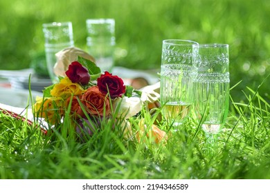 In The Grass Are Champagne Glasses And A Bouquet Of Flowers For A Special Occasion