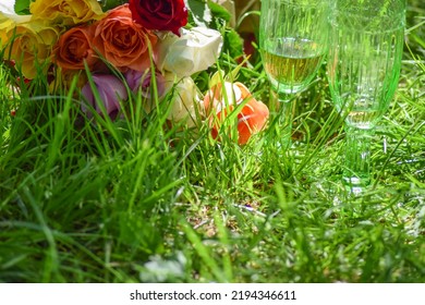 In The Grass Are Champagne Glasses And A Bouquet Of Flowers For A Special Occasion