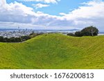 Grass covered crater of mount eden with the background of cityscape of downtown Auckland New Zealand 