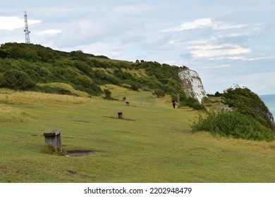 A Grass Field With Several Stone Benches On The Top Of The White Cliffs Of Dover