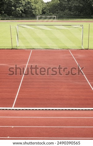 Leerer Tennisplatz mit Ballwagen und leuchtend rotem Belag