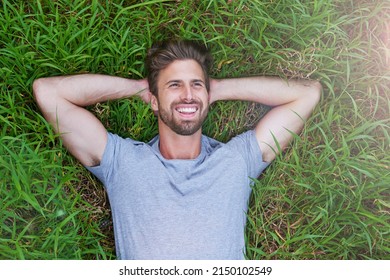 The grass is greener on the other side. High angle shot of a young man lying down on the grass with his hands behind his head.