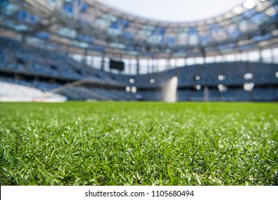 Grass On Stadium In Sunlight. Closeup Of A Green Football Field. Wet Stadium Grass In The Morning Light During Watering Irrigation. Close Up Macro Of Soccer Or Football Field. Green Grass Field