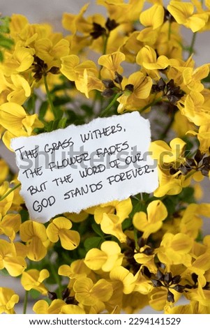 Grass withers, flower fades, the Word of God stands forever, handwritten verse note with spring flowers. A closeup. Isaiah 40:8 Scripture, faith and hope in God Jesus Christ. Biblical concept.