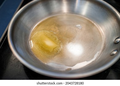 Grass-fed butter melting in stainless steel frying pan at high heat closeup for cooking sauteing