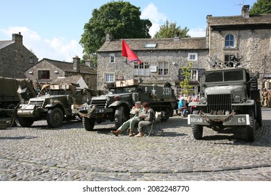 Grassington, Yorkshire, England, Britain, Sep 19th 2015. Participants in 1940s Nostalgia event stop for lunch in Grassington village square in front of old style American vehicles.   