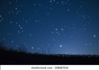 A Grassy Hill Under A Starry Night Sky.