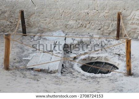 The grate is embedded within a rough, irregularly shaped concrete or cement structure.