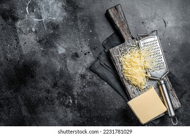 Grated cheese for cooking on a cutting board . Black background. Top view. copy space. - Powered by Shutterstock