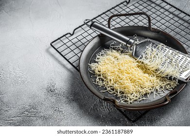 Grated cheese for cooking in a steel tray with grater. White background. Top view. copy space.