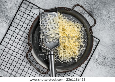 Grated cheese for cooking in a steel tray with grater. White background. Top view.