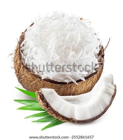 Grated coconut pulp in cracked coconut shell with green leaves and piece of coconut near it isolated on white background.  