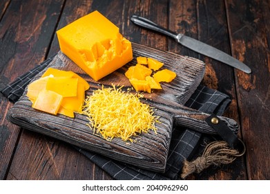 Grated and diceded Cheddar Cheese on a wooden chopping board. Dark wooden background. Top view - Powered by Shutterstock