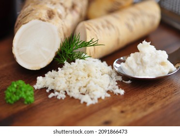 Grated horseradish with parsley on wooden table.
