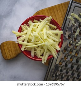 Grated Monterrey Jack Cheese In Red Ceramic Bowl. 