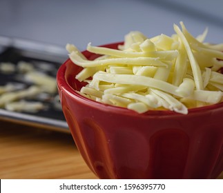 Grated Monterrey Jack Cheese In Red Ceramic Bowl. 