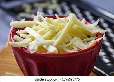 Grated Monterrey Jack Cheese In Red Ceramic Bowl. 