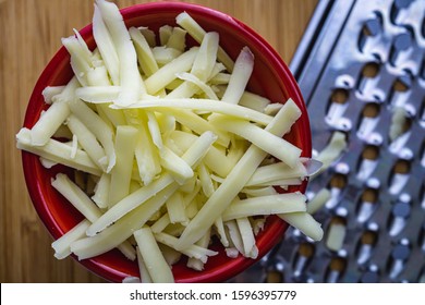 Grated Monterrey Jack Cheese In Red Ceramic Bowl. 