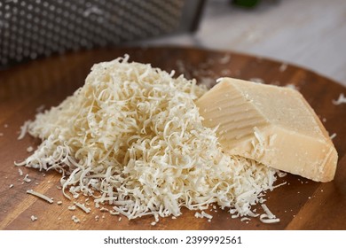 Grated parmesan block in closeup shot, on a rustic wooden chopping board - Powered by Shutterstock