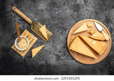 grated parmesan cheese and metal grater on a dark table, Parmesan is hard cheese uses in pasta dishes, soups, risottos and grated over salads. top view. - Shutterstock ID 2291501295
