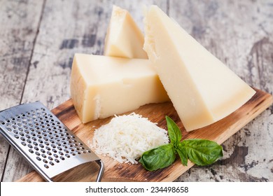 Grated Parmesan Cheese And Metal Grater On Wooden Board