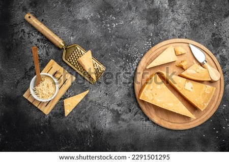 grated parmesan cheese and metal grater on a dark table, Parmesan is hard cheese uses in pasta dishes, soups, risottos and grated over salads. top view.