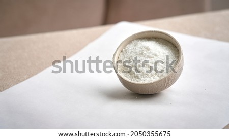 Grated and whole young coconut. view of grated coconut in ceramic bowl on white background.