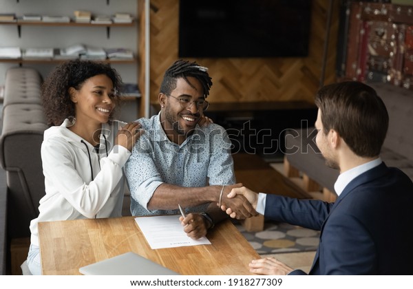 Grateful black family couple handshake with bank\
manager insurer lawyer thank for consultation before sign contract.\
Satisfied young african husband wife real estate buyers make deal\
with male broker