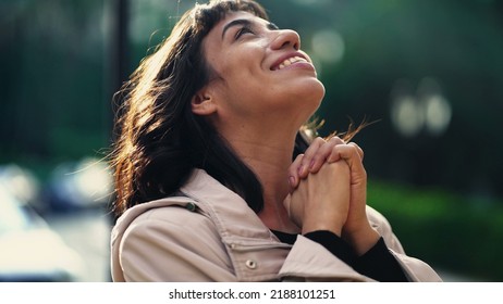 A grateful hispanic woman praying to God with hands clenched looking at sky smiling. Spiritual person having HOPE