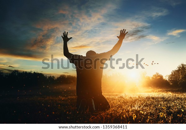 Grateful man man raising his hands in\
worship in the\
countryside.