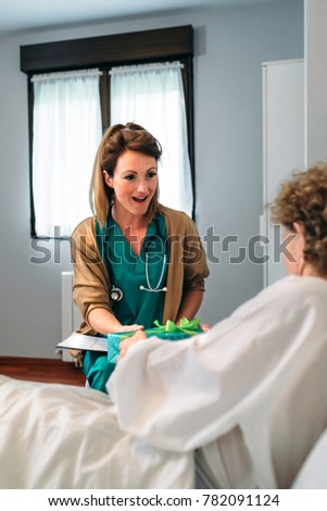 Grateful senior female patient giving gift to female doctor