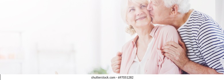 Grateful Senior Man Kissing His Happy Older Wife In The Cheek