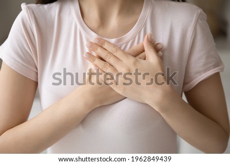 Grateful young woman applying hands on chest, expressing love, honesty. Cropped shot of girl in casual t-shirt making gratitude arms heart, thanking, sympathy, acknowledgement gesture. Close up