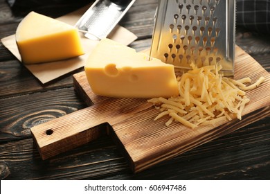 Parmesan Cheese And Grater Close Up. An Angled View Of A Block Wedge Of  Parmesan Cheese With Shredded Pieces All Around And A Metal Cheese Grater  On A Cutting Board Stock Photo