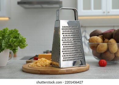 Grater, cheese and vegetables on table in kitchen