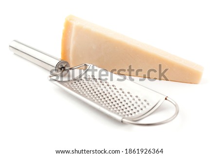 A grater and one piece of parmigiano cheese. Studio photo isolated on white background.