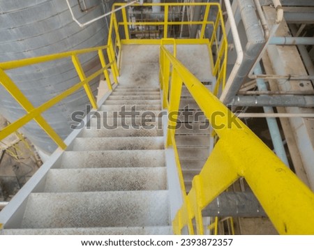 grating stairs with yellow handrail in factory area