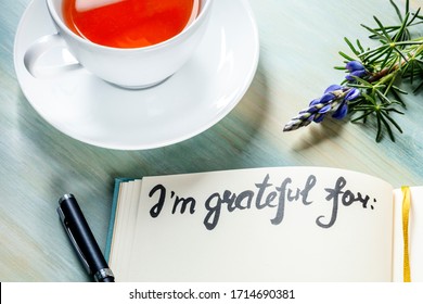 Gratitude Journal With A Flower And A Cup Of Tea, With The Handwritten Phrase I Am Grateful For