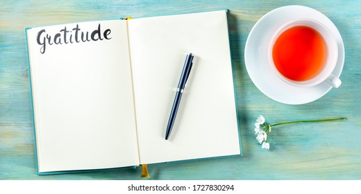 Gratitude Journal Panorama With A Pen, A Flower, And A Cup Of Tea, Shot From Above, With The Hand Written Word